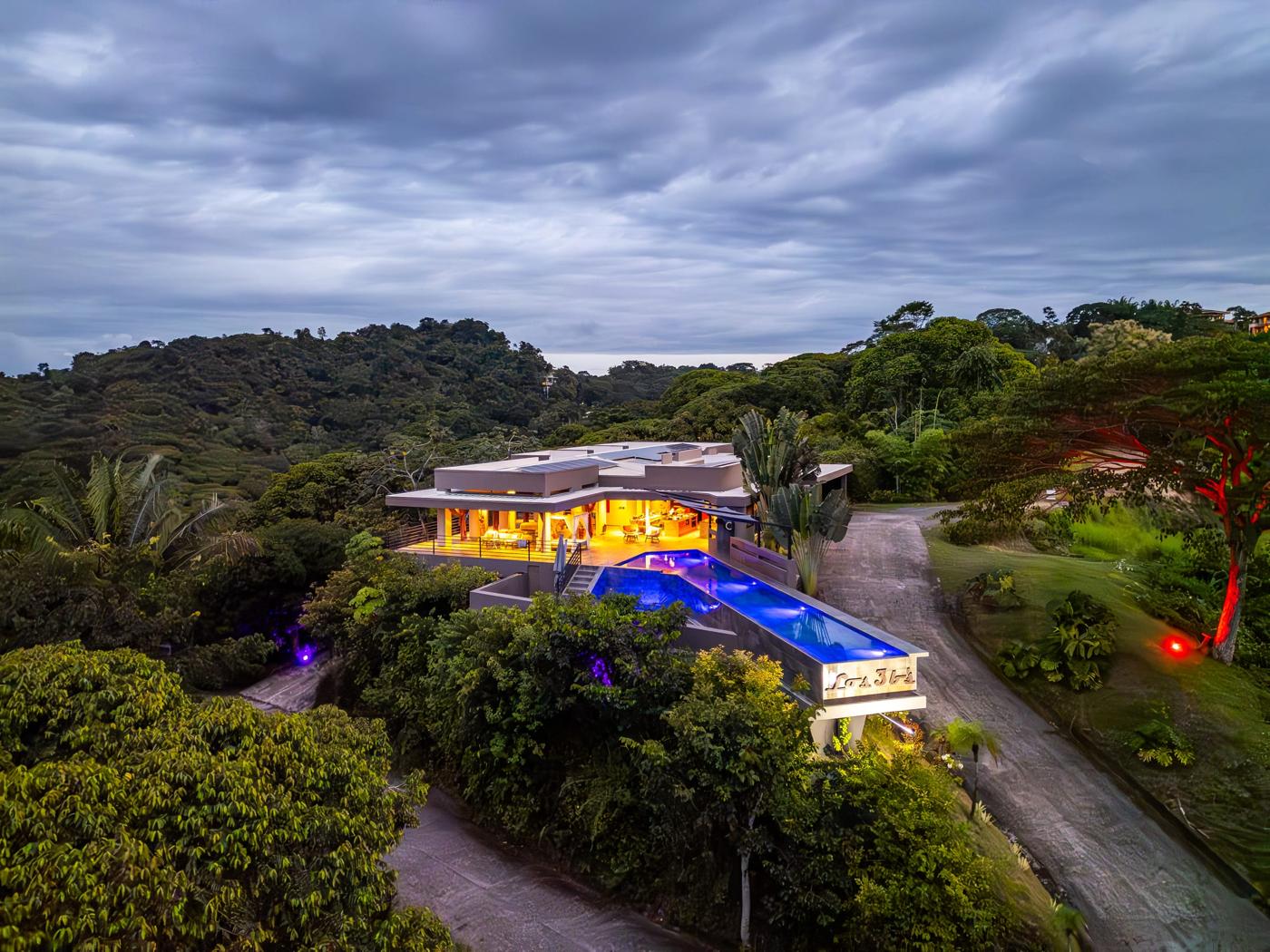 Villa Los 3bs lit up at dusk on its ridge, the pool glowing blue