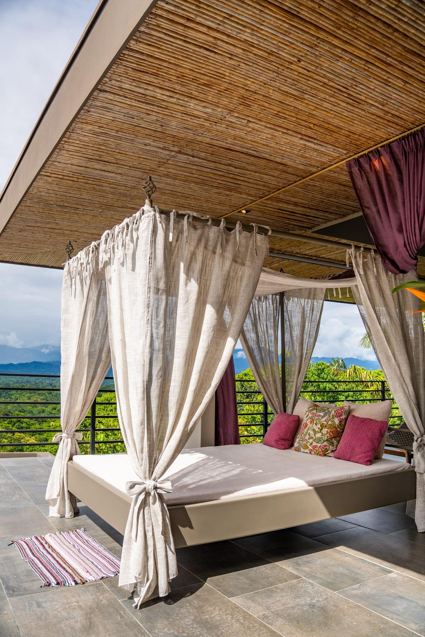 A canopy bed with white curtains on the open deck