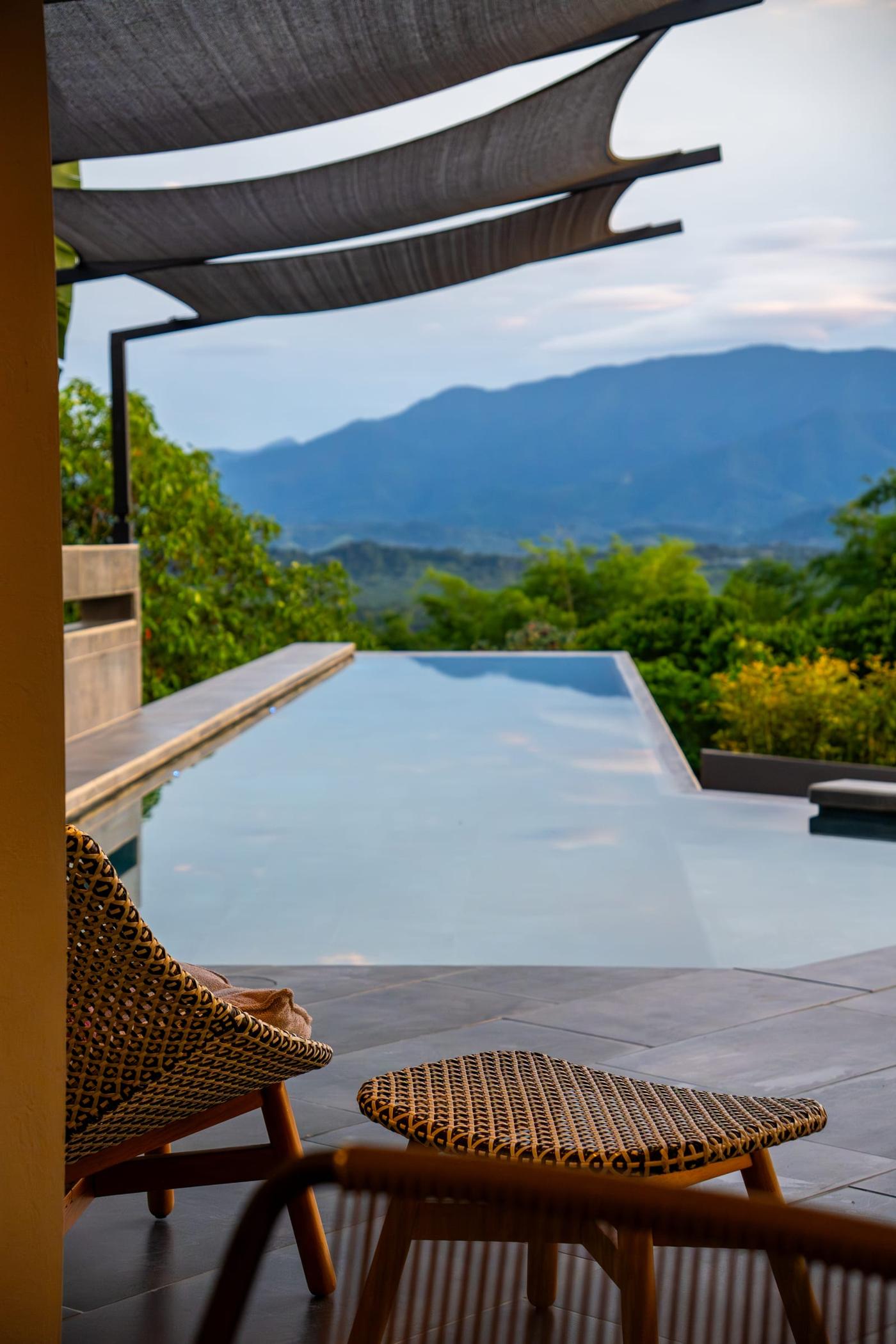 The infinity pool at first light, a lounge chair in the foreground and the mountains behind