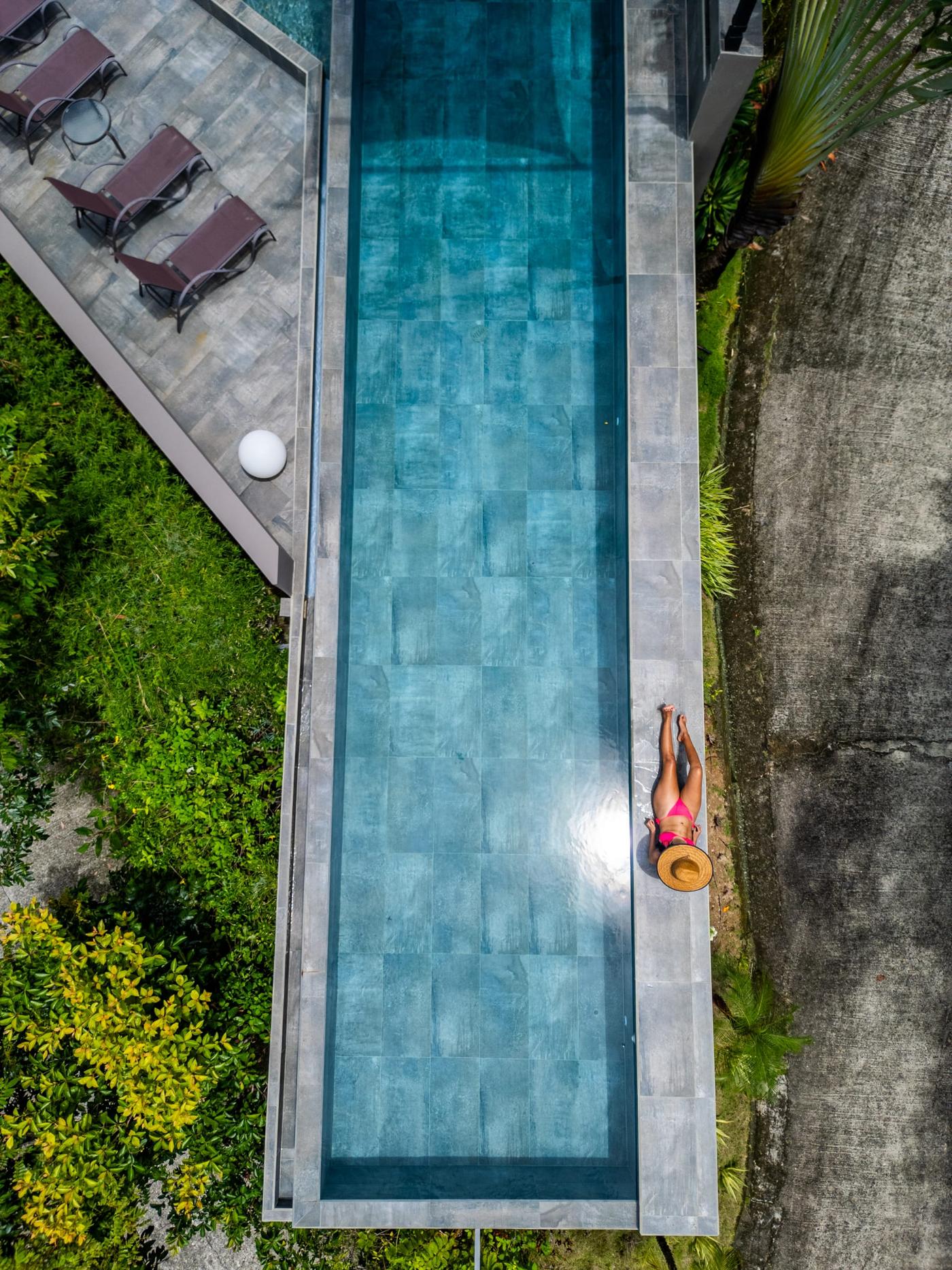 The 20-metre infinity pool seen straight down from the drone, a guest lying at its edge